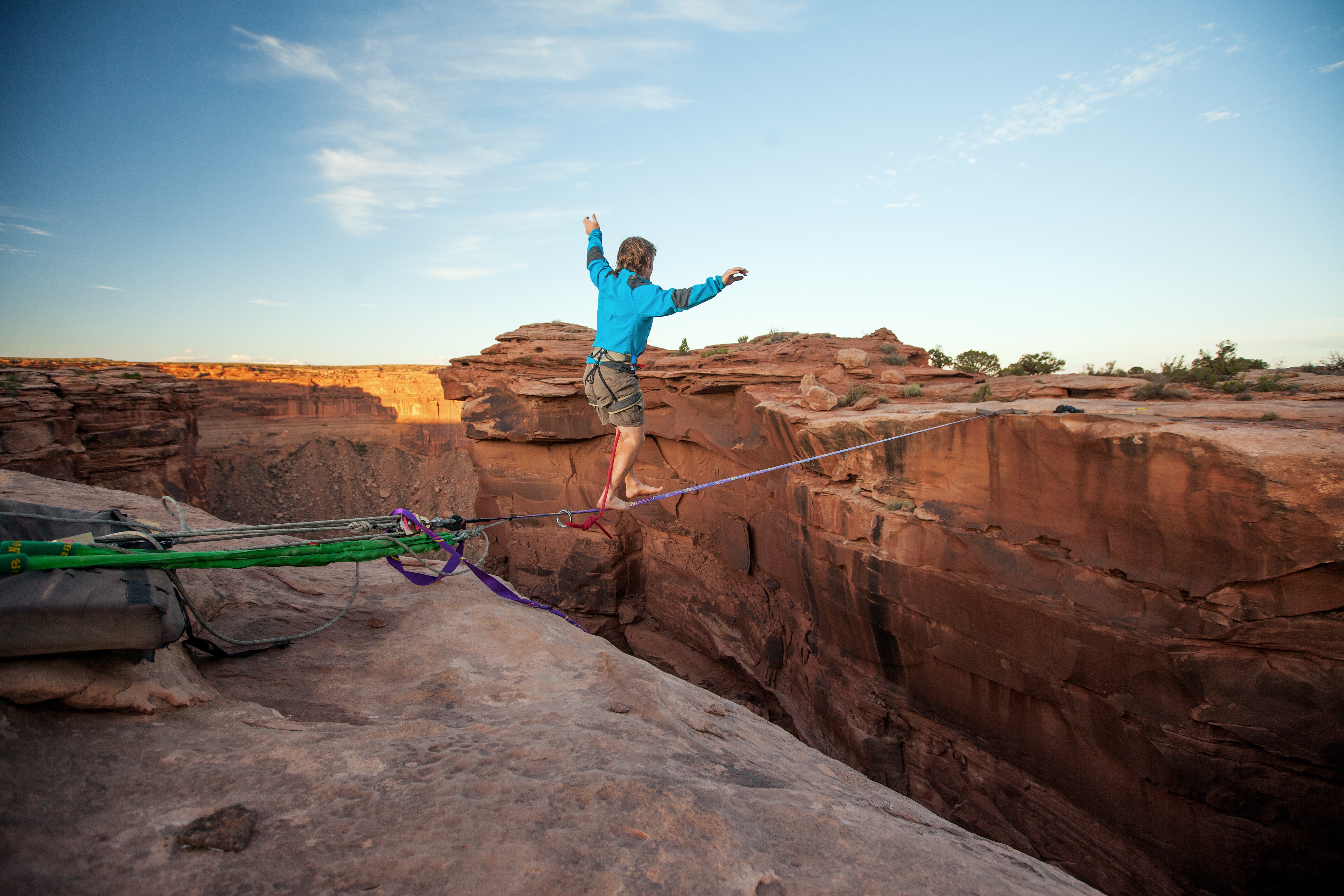 Guy walking on a line over a canyon in Moab.